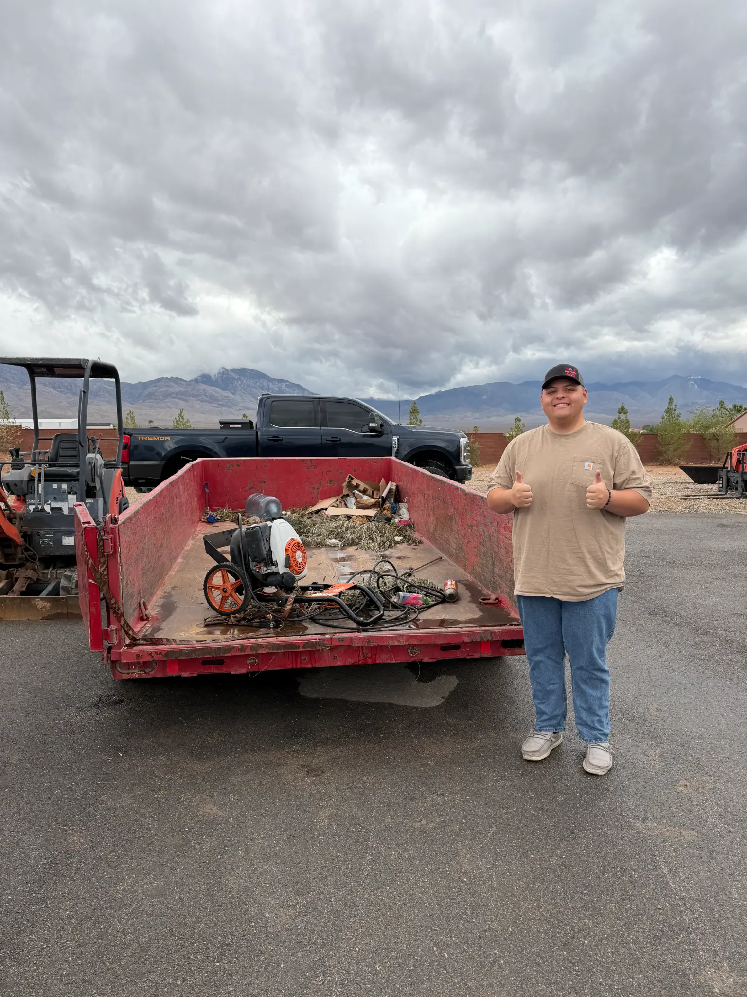 KC’s Junk Removal team member beside a red trailer loaded with items for removal